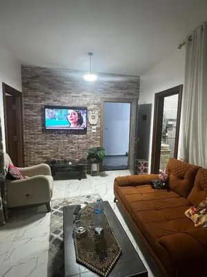 a living room with a couch and a tv on a brick wall at 2 bedroom apartment in Prestige Plaza in Hurghada