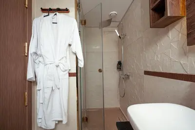 a white robe is hanging in a bathroom at Shepherd I Dahabya in Esna