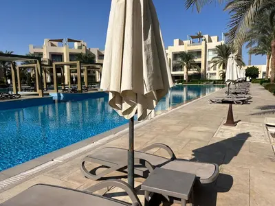 a umbrella and chairs next to a swimming pool at SunShine M9 Mangroovy in Hurghada
