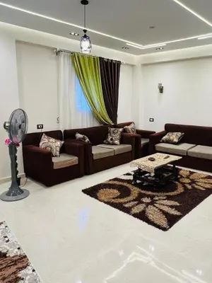 a living room with couches and a table and a fan at Fontana Guste house in Luxor