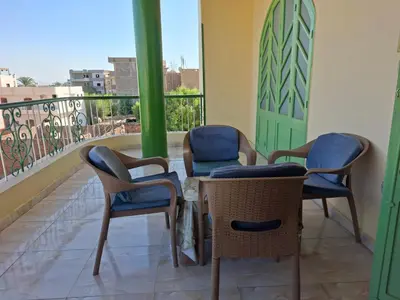 a balcony with three chairs and a table with a view at Villa Joanna in Luxor