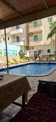 a large swimming pool in a hotel with a table at Villa Joanna in Luxor