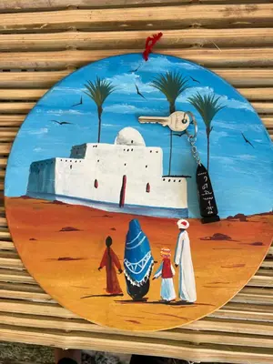a plate with a painting of people and a castle at NubaNest GuestHouse in Aswan