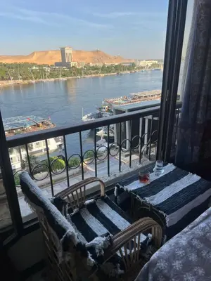 a view of a river from a balcony with a bench at NubaNest GuestHouse in Aswan