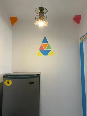 a triangle sign on a wall next to a refrigerator at NubaNest GuestHouse in Aswan