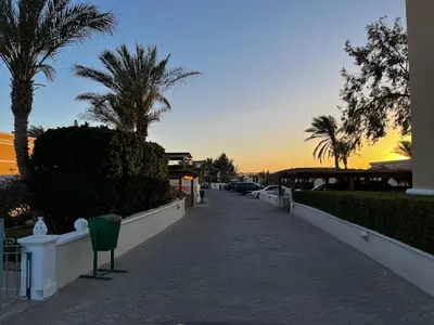 a sidewalk with palm trees and a sunset in the background at Hillside 4BR Villa, El Gouna Getaway in Hurghada