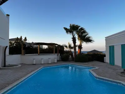 a swimming pool in front of a house with a palm tree at Hillside 4BR Villa, El Gouna Getaway in Hurghada