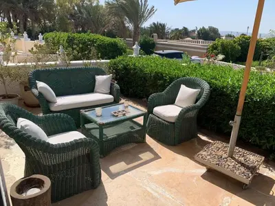 a patio with three chairs and a table and an umbrella at Unique Hill Villa 3 BD In Gouna in Hurghada