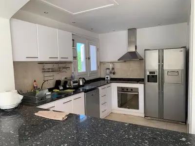 a kitchen with white cabinets and a stainless steel refrigerator at Unique Hill Villa 3 BD In Gouna in Hurghada