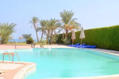 a large swimming pool with palm trees and umbrellas at Elite Sea Sky Resort in Hurghada