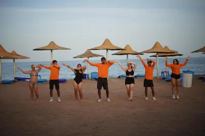 a group of people standing on the beach under umbrellas at Elite Sea Sky Resort in Hurghada