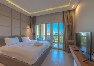 a bedroom with a bed and a television and a balcony at Upscale 2BR Mosaique Marina Stay, Yachts & Sea Views in Hurghada