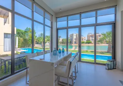 a dining room with a view of a swimming pool through windows at Airy & Bright 4BR Villa in Tawila, El Gouna, Private Pool & Lagoon Access in Hurghada