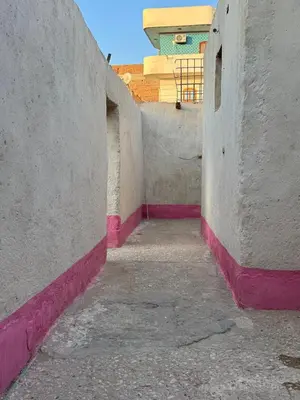 an alley between two buildings with pink and white walls at Mountain house retreat in Al Aqālitah