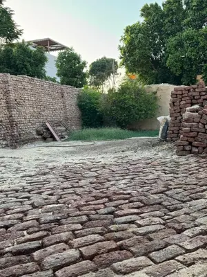 a cobblestoneicked yard with a brick wall and trees at Mountain house retreat in Al Aqālitah