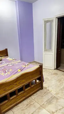 a bedroom with a wooden bed with a purple blanket at Diebo in Aswan