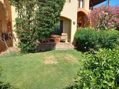 a house with a table and a chair on the porch at Peaceful & bright lagoon escape - Shared infinity Pool - 1BR - Sabina, El Gouna in Hurghada