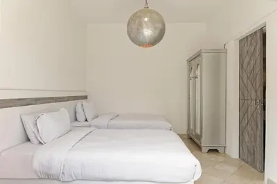 a white bedroom with two beds and a chandelier at VESTA - El Gouna Residence in Hurghada