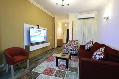a living room with a couch and a flat screen tv at Magawish Bliss , Elegant Hurghada Apartment in Hurghada