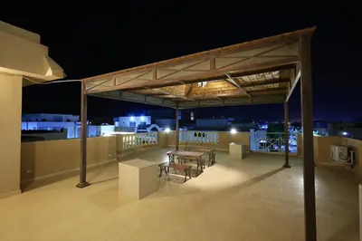 a rooftop deck with a table and chairs at night at Magawish Bliss , Elegant Hurghada Apartment in Hurghada