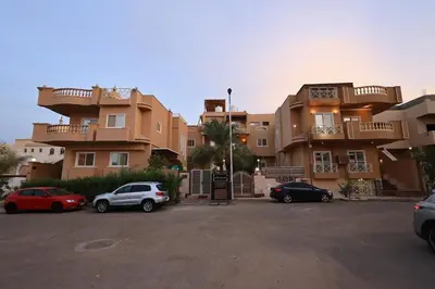 a group of buildings with cars parked in a parking lot at Magawish Bliss , Elegant Hurghada Apartment in Hurghada