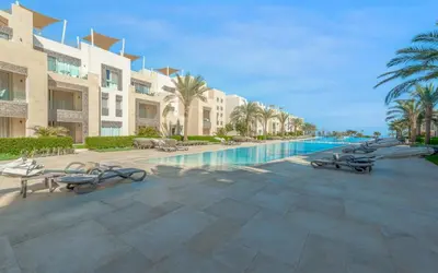 a resort with a swimming pool with palm trees and buildings at New 1BR Apartment in Mangroovy El Gouna Pool, Beach, The Red Sea in Hurghada