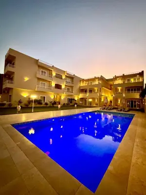 a large blue swimming pool in front of a building at Royal Nile Villa - Luxury Nile Sky Penthouse 2 in Al Aqālitah