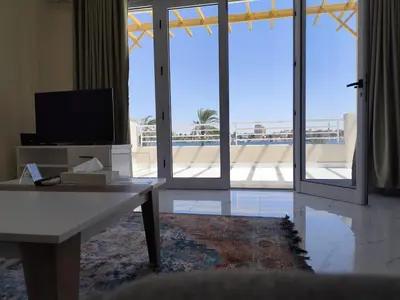 a living room with a tv and a large window at Royal Nile Villa - Luxury Nile Sky Penthouse 2 in Al Aqālitah