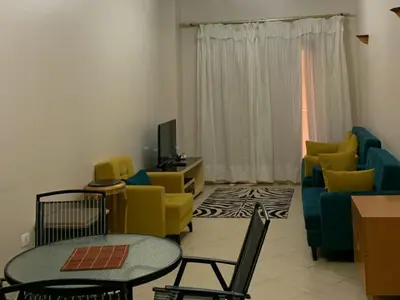 a living room with yellow chairs and a television at One-Bedroom Chalet with Side Sea View , Turtles Beach C23 in Hurghada