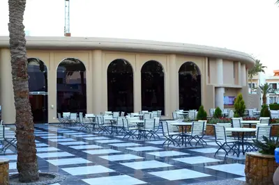 a group of tables and chairs on a patio at Mirage Bay Resort Aquapark SAM Suite in Hurghada