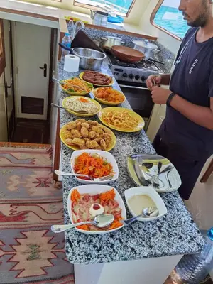 a man standing in front of a buffet of food at رحلات بحرية دولفين وغواصة وجزر in Hurghada