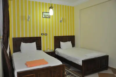 two beds in a room with yellow and white stripes at White Villa in Luxor