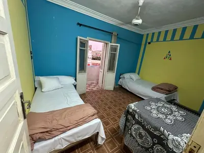 two beds in a room with blue walls at SolNest Guest House in Jazīrat Aswān