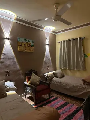 a room with two beds and a ceiling fan at SolNest Guest House in Jazīrat Aswān