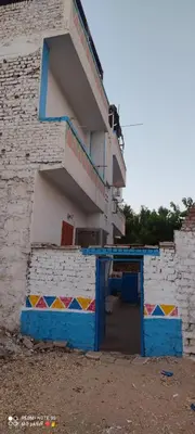 a building with a blue door and a staircase at SolNest Guest House in Jazīrat Aswān