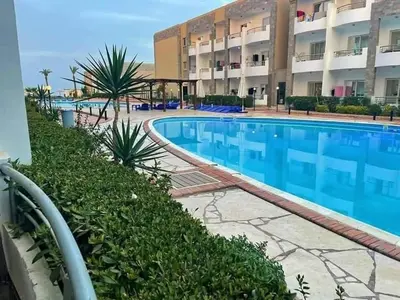 a large swimming pool in a resort with a building at Cecilia Resort Hurghada in Hurghada