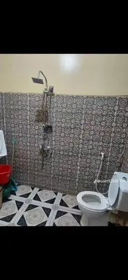 a bathroom with a toilet and a tiled wall at Aswan in Naj‘ al Maḩaţţah