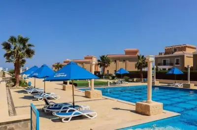 a pool at a resort with blue umbrellas and chairs at 2bedroom in selena bay resort in Hurghada