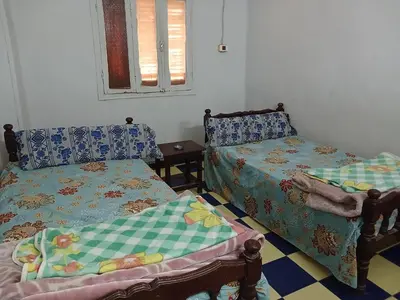 a room with two beds and a table and a window at New Alsalam Hotel in Luxor