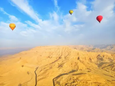 three hot air balloons are flying over the desert at New Alsalam Hotel in Luxor