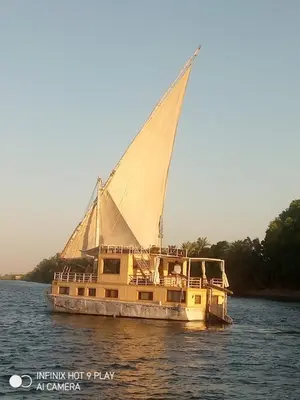 a boat with a sail on the water at King Arthur luxury Dahabyaa in Luxor