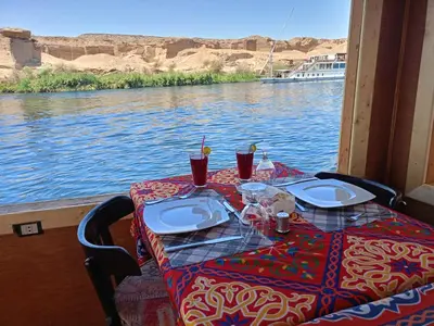 a table on a boat with a view of the water at King Arthur luxury Dahabyaa in Luxor