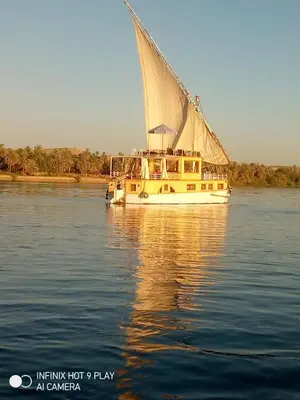 a boat with a large sail on the water at King Arthur luxury Dahabyaa in Luxor
