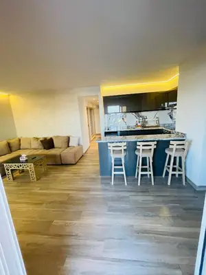 a living room with a couch and a kitchen with stools at New Marina Luxury Suite in Hurghada