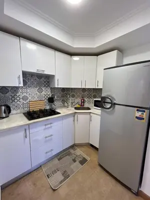 a kitchen with white cabinets and a stainless steel refrigerator at Cozy One bedroom old town tawaya Sahel hashish in Hurghada