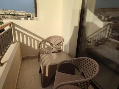 a balcony with a chair and a table and a window at Aldau Heights Hurghada in Hurghada