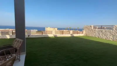 a balcony with a green lawn and the ocean at Azzurra villa in Hurghada