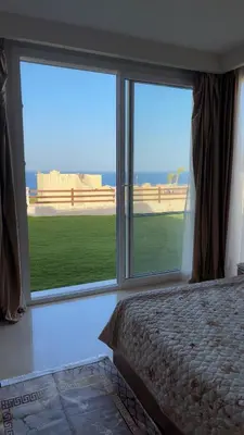 a bedroom with two large windows and a bed at Azzurra villa in Hurghada