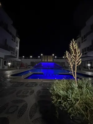 a swimming pool at night with a tree in the middle at Magawish resort in Hurghada