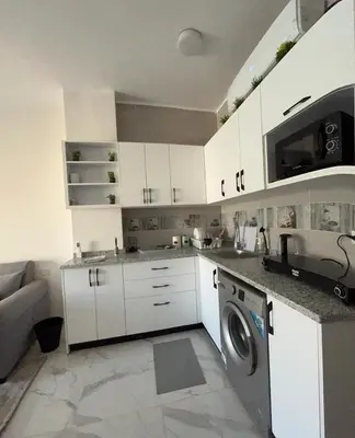 a kitchen with white cabinets and a washing machine at Magawish resort in Hurghada